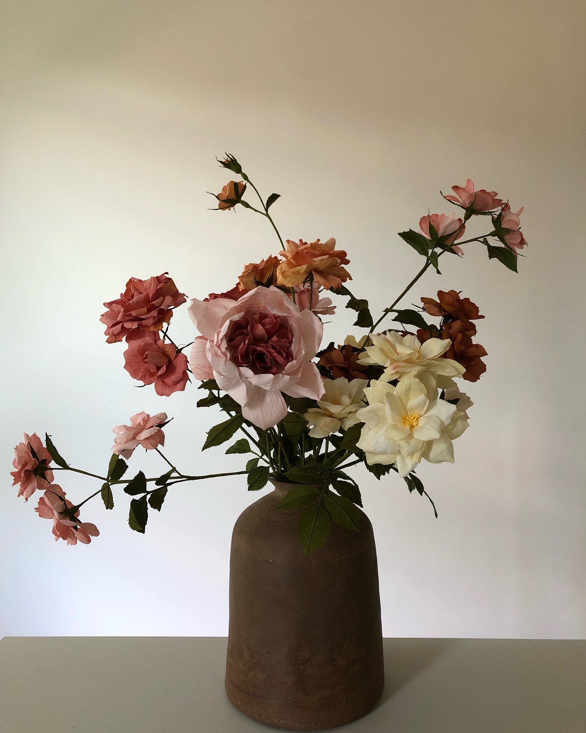 Pink and beiges paper roses in a brown vase